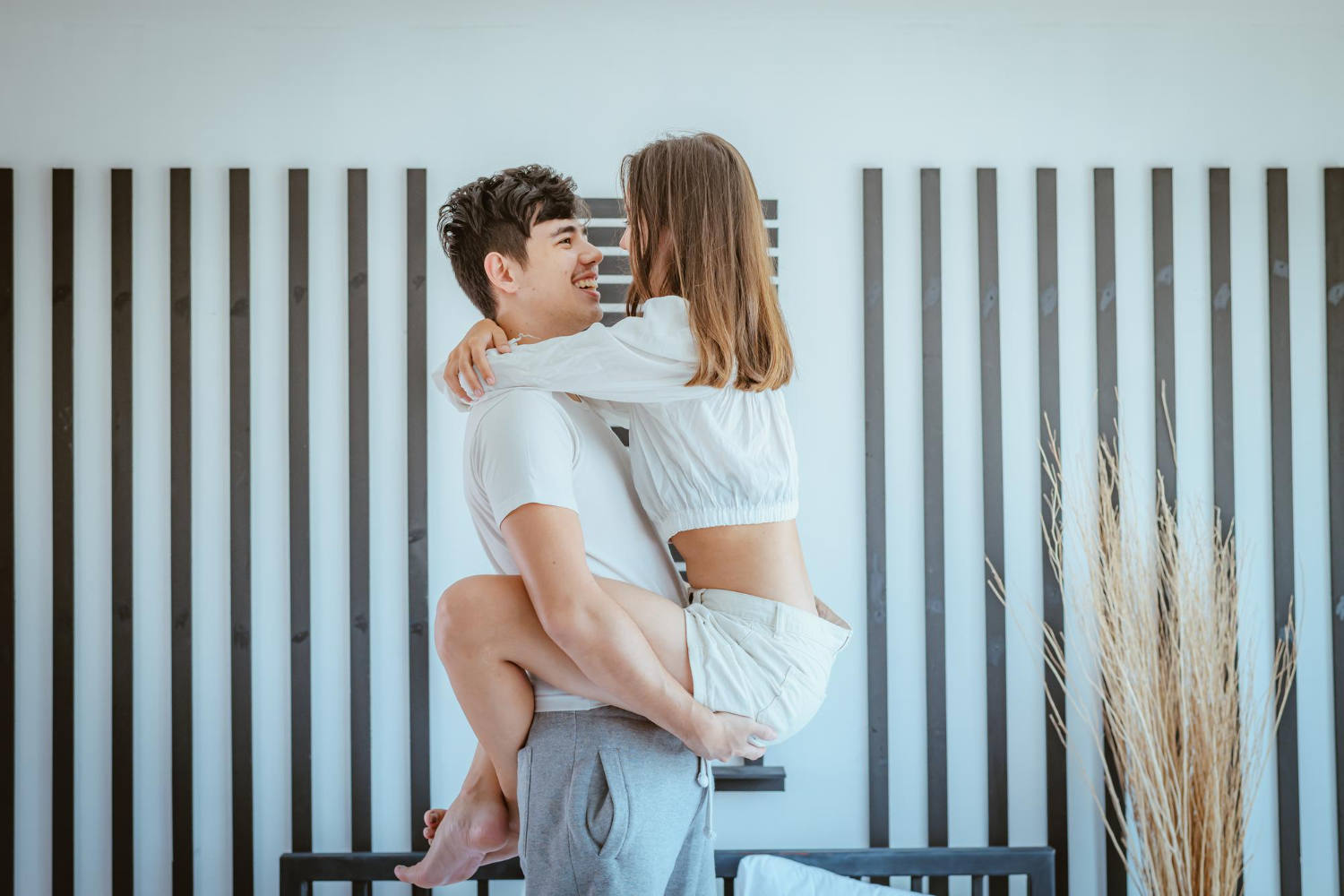 хлопець тримає дівчину на руках і сміється