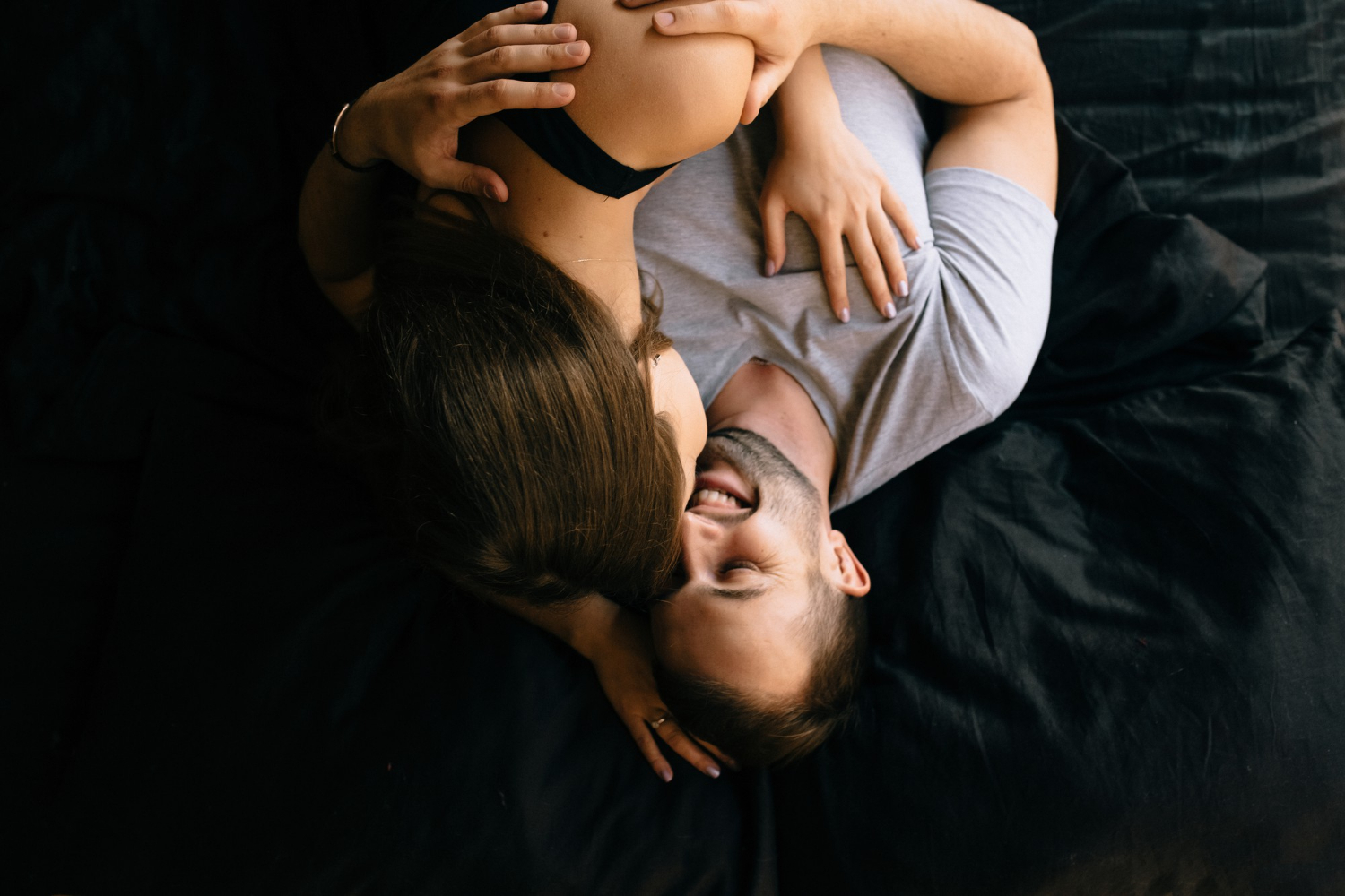 дівчина лежить на хлопці в ліжку і вони сміються